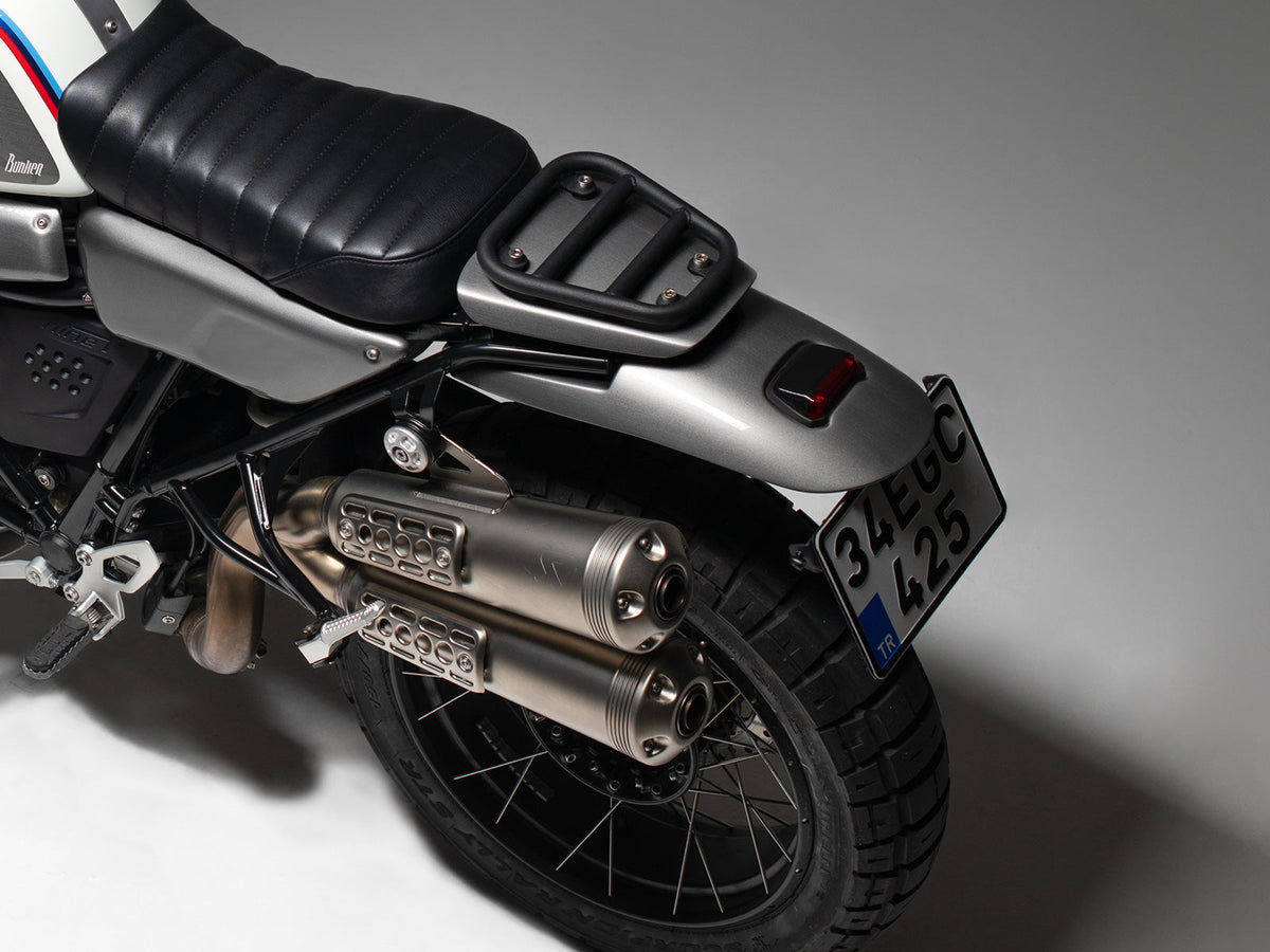 BMW R nineT Black motorcycle fender with Retro red Stop light Close-up of a motorcycle's exhaust and license plate on a gray background