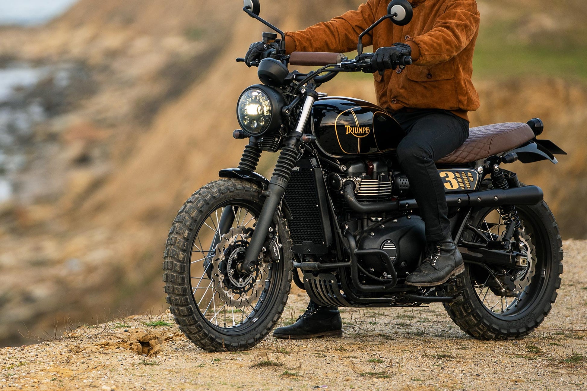 Triumph Radiator Guard Black eng'ne guard Person sitting on a motorcycle in a desert-like setting